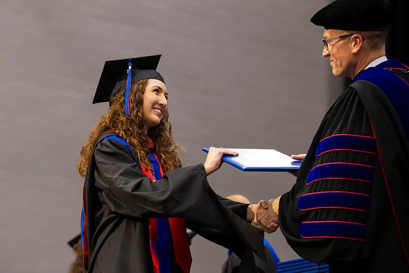 Dr. Brendan Kelly, 澳门新普京注册 president, hands a graduate her degree